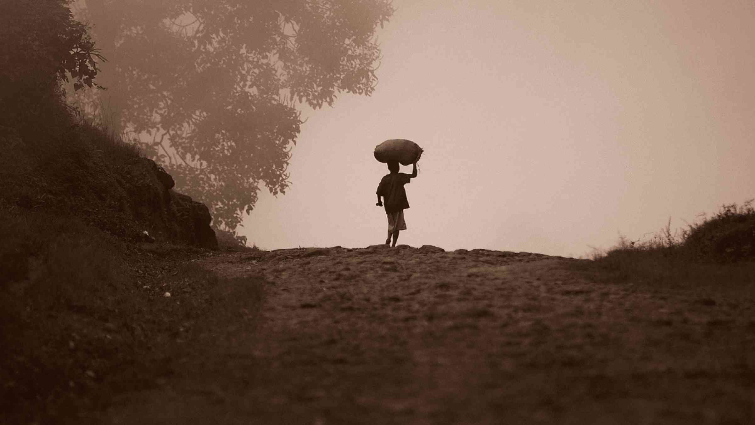 Person carrying a bag of grain